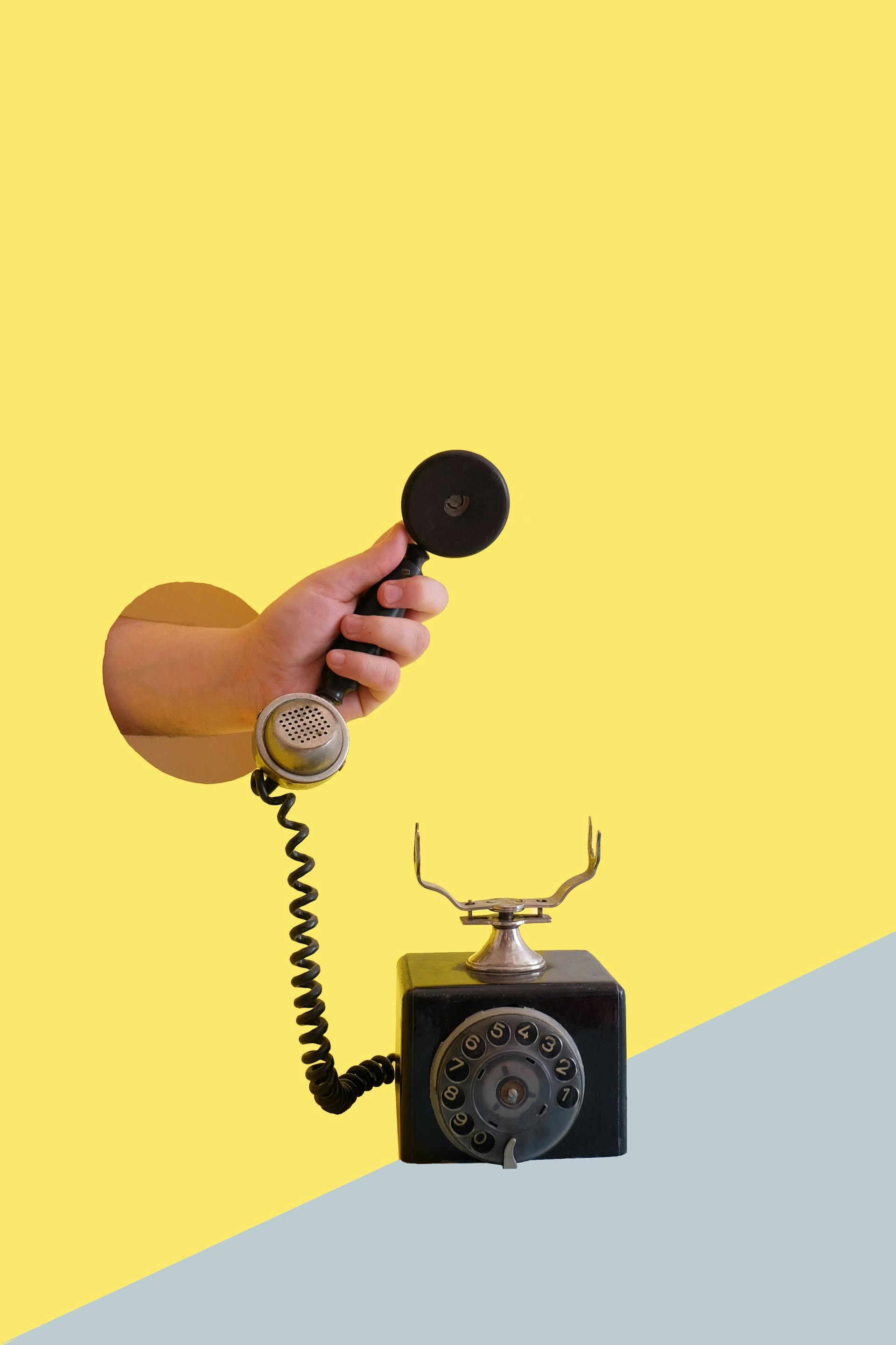person holding black rotary telephone receiver